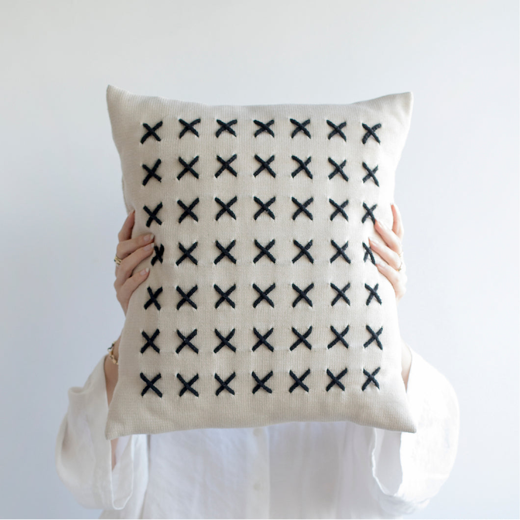 Add a little bit of style and personality to your home with the X cushion. By playing with the negative spaces to create a unique feeling, the X cushion offers timeless aesthetic with a bold repetitive pattern.  Disclaimer: Every cushion is individually knitted and sewn by hand to ensure the highest level of comfort and long-lasting quality, which means you may find slight variations in design and size.  Cushion filling included. 42 x 42 cm 100% polyester